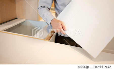 Male hand furniture assembler installing cabinet panel 107441932