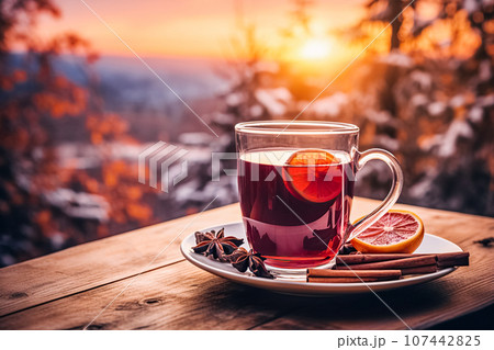 Traditional winter warming Christmas drink mulled wine with orange slices and spices against backdrop of winter forest 107442825