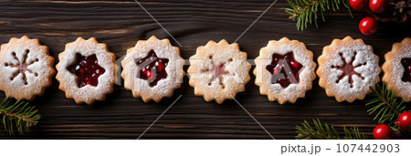 Linzer cookies with sweet jam and fir tree branches on wooden table. Top view 107442903