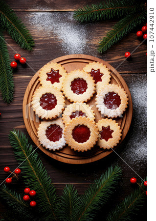 Linzer cookies with sweet jam and fir tree branches on wooden table. Top view 107442910