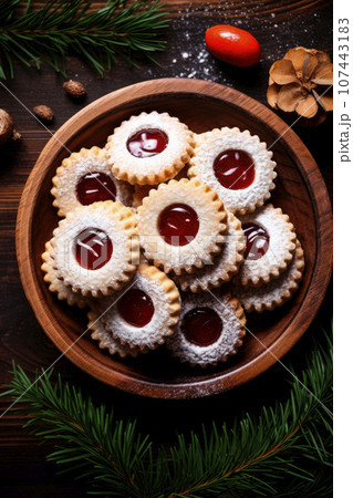 Linzer cookies with sweet jam and fir tree branches on wooden table. Top view 107443183