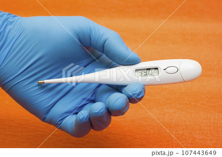 Hand medical glove holds electronic thermometer - temperature measurement, coronavirus, covid19 Hand medical glove holds electronic thermometer - temperature measurement, coronavirus, covid19 107443649