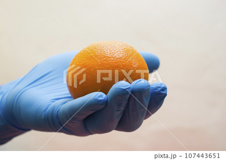Hand in medical glove holds an orange - vitamin, coronavirus, covid19 Hand in medical glove holds an orange - vitamin, coronavirus, covid19 107443651