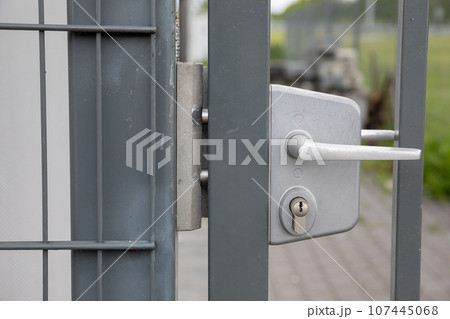 A close-up front view of the white handle on the steel fence gate. A close-up front view of the white handle on the steel fence gate. 107445068