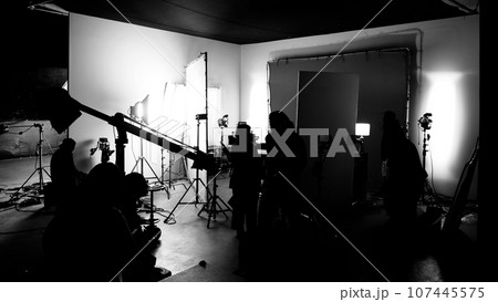 Silhouette images of making of or behind the scenes of video production which produced in the film studio that include all pro light and camera equipment and professional film crew with movie director 107445575