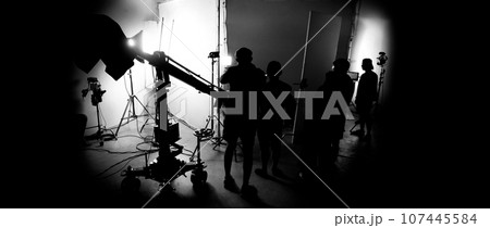 Silhouette images of making of or behind the scenes of video production which produced in the film studio that include all pro light and camera equipment and professional film crew with movie director Silhouette images of making of or behind the scenes of video production which produced in the film studio that include all pro light and camera equipment and professional film crew with movie director 107445584