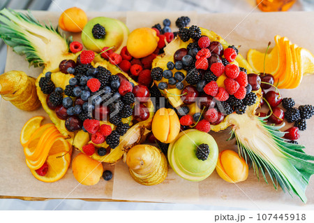 Beautiful and original serving of fruits and berries in pineapple.  107445918