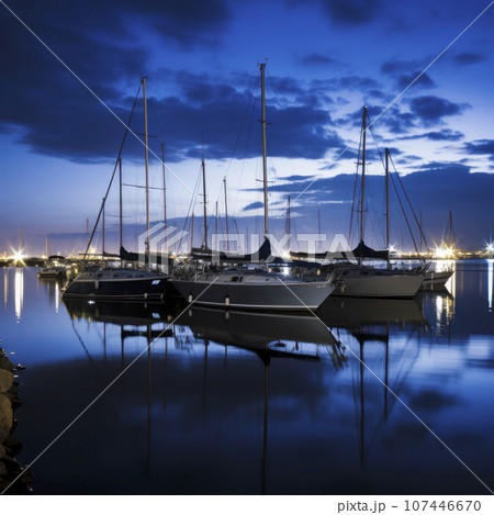 sailboats anchored in a harbor at night sailboats anchored in a harbor at night 107446670