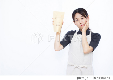 白い背景の前で給料袋を持ち悩んでいる30代の主婦 白い背景の前で給料袋を持ち悩んでいる30代の主婦 107446874