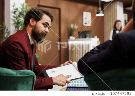 Multinational team sharing new ideas and similar management experiences, embracing cultural diversity at international business conference. Businessmen discusing in hotel lounge area. 107447593