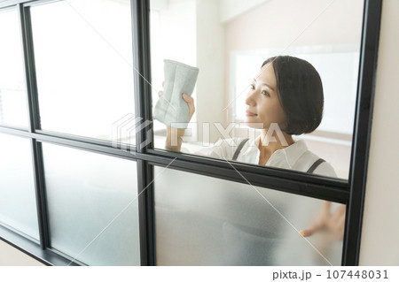 窓拭きをするエプロン姿の女性 窓拭きをするエプロン姿の女性 107448031
