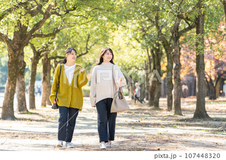 秋の公園で散歩する女性 107448320