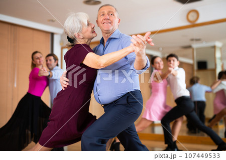 Happy older couple performing a paired ballroom dance in ballroom Happy older couple performing a paired ballroom dance in ballroom 107449533