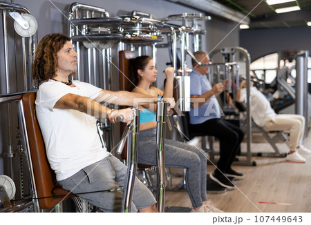 Athletic man is engaged in simulator - develops biceps and triceps 107449643