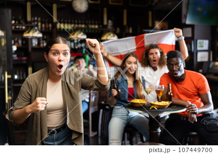 Happy international soccer supporters holding up the flag of England with beer in the pub Happy international soccer supporters holding up the flag of England with beer in the pub 107449700