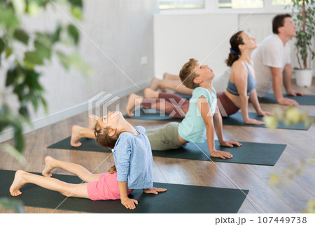Mom, dad, son and daughter perform pose dog muzzle up - cobra, Urdhva Mukha Shvanasana- Bhujangasana Mom, dad, son and daughter perform pose dog muzzle up - cobra, Urdhva Mukha Shvanasana- Bhujangasana 107449738