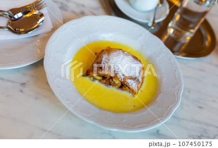 Slice of Viennese apple strudel served with vanilla sauce 107450175