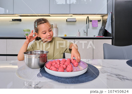 A girl is preparing meatballs in the kitchen. A girl is preparing meatballs in the kitchen. 107450624