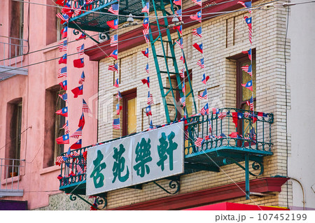 White and green sign attached to green fire escape with American and Chinese flags White and green sign attached to green fire escape with American and Chinese flags 107452199