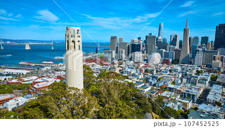 Aerial capturing the bay and Oakland Bay Bridge with Coit Tower close up and city skyscrapers Aerial capturing the bay and Oakland Bay Bridge with Coit Tower close up and city skyscrapers 107452525