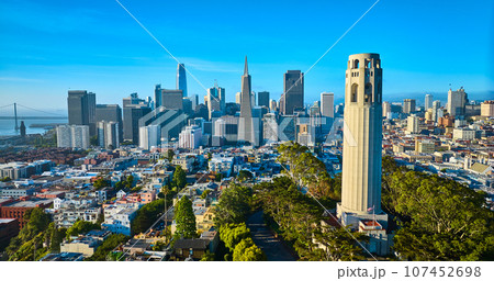 Aerial Coit Tower in late afternoon with downtown San Francisco skyscrapers and distant bridge Aerial Coit Tower in late afternoon with downtown San Francisco skyscrapers and distant bridge 107452698