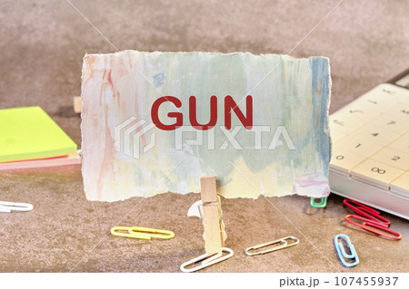GUN text on a piece of paper on the table with a clothespin clamped GUN text on a piece of paper on the table with a clothespin clamped 107455937