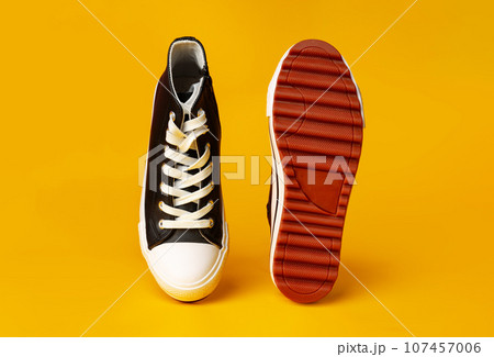 New black and white canvas sneakers on yellow background New black and white canvas sneakers on yellow background 107457006