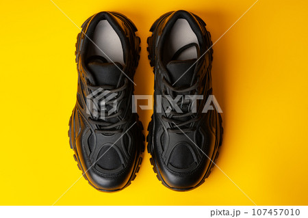 Black new sport sneakers on yellow background Black new sport sneakers on yellow background 107457010