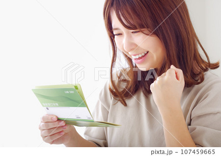 貯金通帳を見て喜ぶ若い女性 107459665
