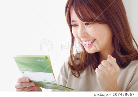 貯金通帳を見て喜ぶ若い女性 107459667