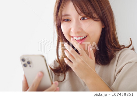 スマホを見て喜びの表情を浮かべる若い女性 スマホを見て喜びの表情を浮かべる若い女性 107459851