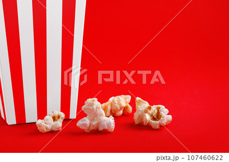 Glass with popcorn on a red background Glass with popcorn on a red background 107460622