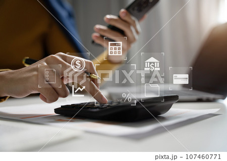 Businesswoman working with smartphone and using a calculator to calculate the numbers of static in office. Finance accounting concept. Businesswoman working with smartphone and using a calculator to calculate the numbers of static in office. Finance accounting concept. 107460771