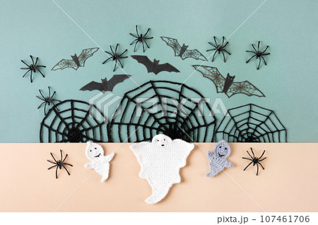 Happy Halloween holiday concept. Halloween decorations, ghost, spiders, bats, knitted webs on green and beige background. Flat lay, top view Happy Halloween holiday concept. Halloween decorations, ghost, spiders, bats, knitted webs on green and beige background. Flat lay, top view 107461706