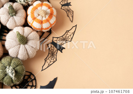 Halloween greeting card mockup with copy space. Halloween decorations, bats, knitted webs, pumpkins on beige background. Happy Halloween holiday concept. Flat lay, top view Halloween greeting card mockup with copy space. Halloween decorations, bats, knitted webs, pumpkins on beige background. Happy Halloween holiday concept. Flat lay, top view 107461708