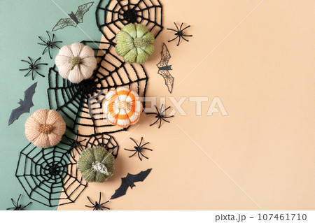 Halloween greeting card mockup with copy space. Halloween decorations, spiders, bats, knitted webs, pumpkins on green and beige background. Happy Halloween holiday concept. Flat lay, top view Halloween greeting card mockup with copy space. Halloween decorations, spiders, bats, knitted webs, pumpkins on green and beige background. Happy Halloween holiday concept. Flat lay, top view 107461710