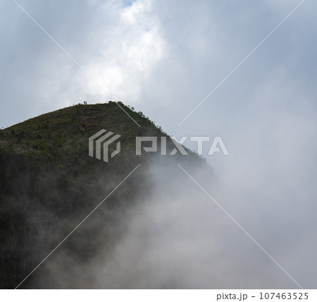 Unrecognizable People at Foggy Mountain Peak Under Cloudy Sky 107463525