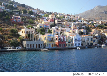 Symi Island, Greece. Greece islands holidays from Rhodos in Aegean Sea. Colorful neoclassical houses in bay of Symi. Holiday travel background 107464753