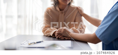 Female nurse hold her senior patient hand. Giving Support. Doctor help patient with disease. Female carer holding hands of senior woman Female nurse hold her senior patient hand. Giving Support. Doctor help patient with disease. Female carer holding hands of senior woman 107464926