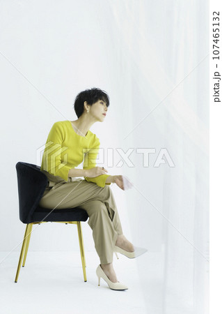 白背景の椅子に座る若い女性の全身のファッションポートレート　縦位置 107465132