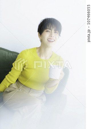 白背景のグリーンのソファに座る黄色い服を着た若い女性のファッションポートレート 縦位置 白背景のグリーンのソファに座る黄色い服を着た若い女性のファッションポートレート 縦位置 107466055