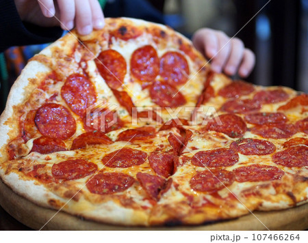 Pizza, delicious appetizing food, children's hands tear off a piece of pizza. Delicious home-made delicacy, small business. 107466264