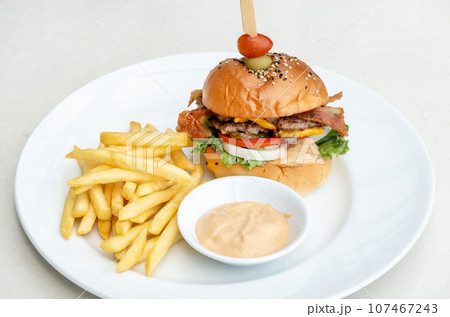 Single cheeseburger with bacon and French fries on table Single cheeseburger with bacon and French fries on table 107467243