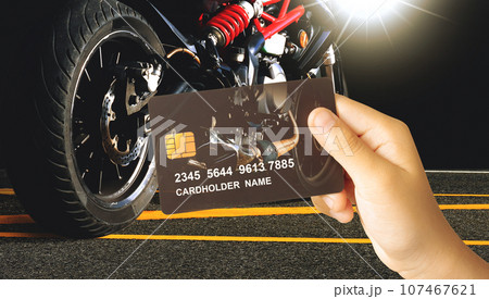 Hand holding a luxury credit or debit card with a motorbike on dark background 107467621