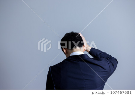 頭を抱える男性の後ろ姿 107467681