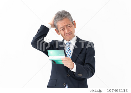 通帳を見る男性　悩む 107468158