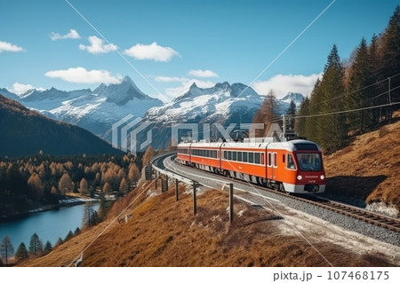 A locomotive pulls a passenger train along a winding road among the autumn forest and mountains. 107468175
