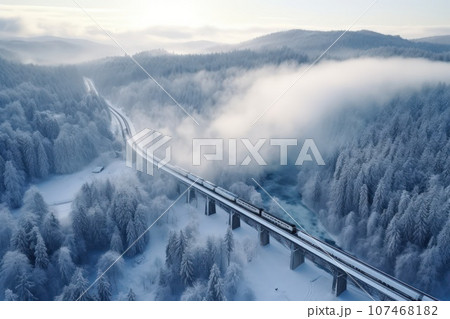 A locomotive pulls a passenger train along a winding road among the winter forest and mountains. A locomotive pulls a passenger train along a winding road among the winter forest and mountains. 107468182