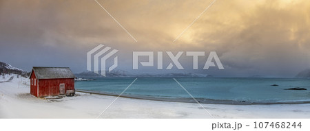 Winter Norway landscape with rorbu on the ocean beach and snow Winter Norway landscape with rorbu on the ocean beach and snow 107468244