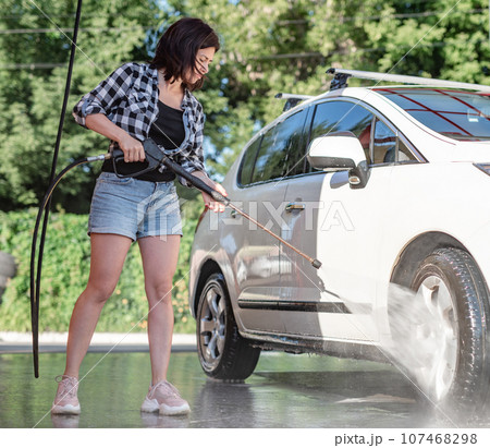 Girl with sprayer on self service car wash 107468298